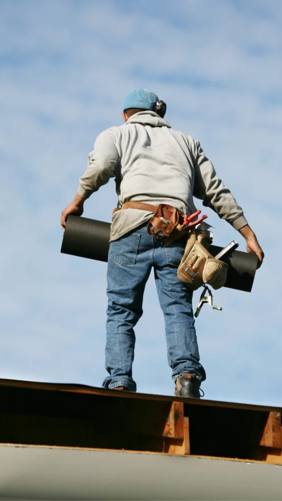 man-on-a-roof-carrying-materials-and-tools-576x1024
